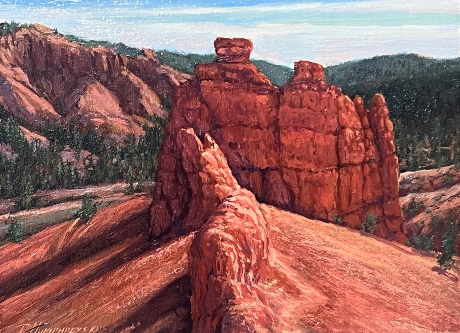 Firestone - Red Canyon Red rock formations with rugged textures and a mountainous backdrop under a blue sky.